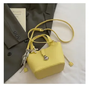 Detalle del bolso de cuero amarillo con cierre de bola plateado y colgante de perro