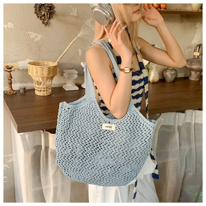 Détail du sac cabas en maille bleu clair montrant la texture tissée et l'étiquette
