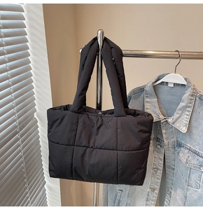Gros plan du sac cabas en velours noir matelassé avec des bandoulières rembourrées et douces
