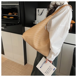 Brown woven leather hobo bag worn on shoulder in a warm home kitchen setting