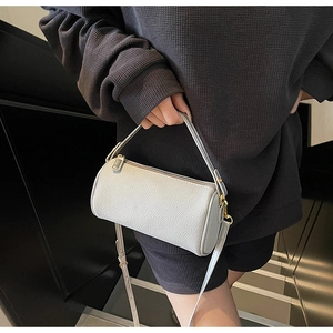 Detail of light grey pebbled leather pillow bag with gold hardware and shoulder strap