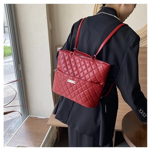 Rear view of a red quilted leather backpack on a model in a minimalist setting