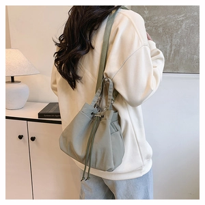 Detailed close-up of bean green nylon bucket bag with drawstring closure and metal buckle