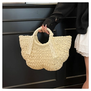 Detail of cream woven straw handbag featuring delicate white lace bow and elegant texture