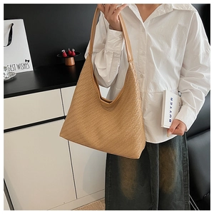 Detail of herringbone woven texture and wide shoulder strap on beige tote bag