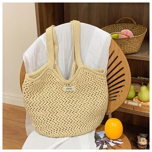Gros plan détaillé d'un sac cabas en crochet beige fait main avec étiquette de marque
