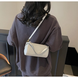 Back view of a model wearing a light grey cylinder bag with lychee grain leather texture