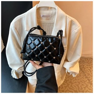 Close-up of black quilted shell bag with silver studs and elegant chain strap detail