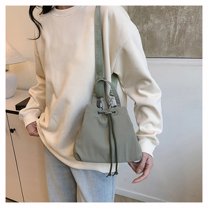 Detail of light green nylon drawstring bucket bag with thick webbing shoulder strap