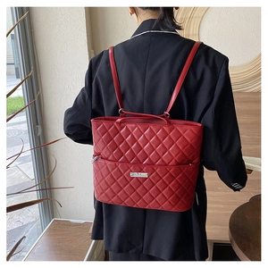 Close-up of quilted pattern on a burgundy shoulder bag with silver logo plaque