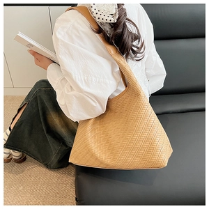 Detailed view of large khaki woven hobo bag with wide shoulder strap and geometric texture