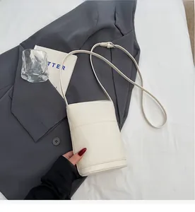 Dettaglio della borsa a secchiello bianco crema con trama litchi e tracolla sottile