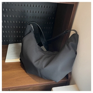 Detail of black crescent hobo bag featuring vertical corduroy texture and silver zipper