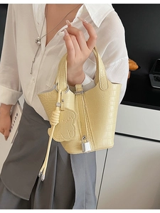 Pale yellow crocodile pattern mini bucket bag with bear pendant and silver padlock detail