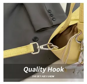 Detalle del gancho plateado en el bolso saco amarillo de textura lichi con correa ajustable