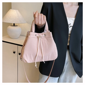 Detail of pink drawstring nylon bucket bag with silver metal eyelets and adjustable strap
