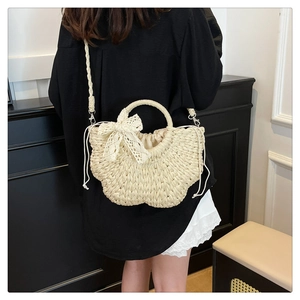 Detail of beige straw crossbody bag with lace bow and drawstring inner lining