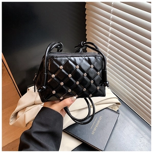 Close-up of black quilted shell bag with sparkling diamonds and knotted shoulder strap