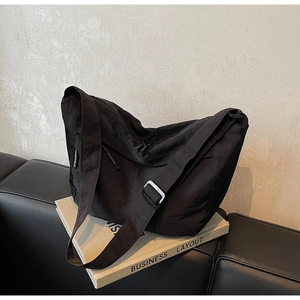 Detail of black nylon crossbody bag with dual zippers and adjustable wide shoulder strap