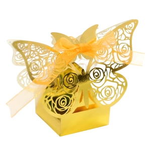 Detail of laser-cut golden favor box with hollow butterfly design and orange ribbon