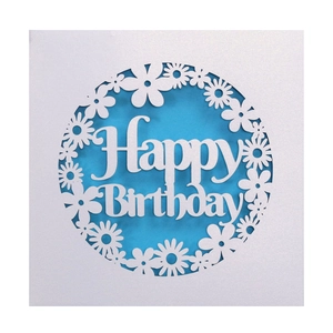 Macro shot of laser-cut daisy flower details and Happy Birthday text on white and blue card