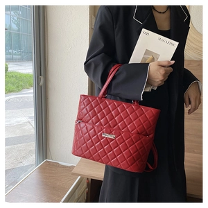 Close-up of red quilted PU leather shoulder bag with silver logo plaque on a model