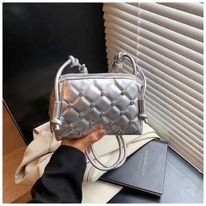 Close-up of silver quilted shell bag featuring rhinestone studs and twisted rope handles