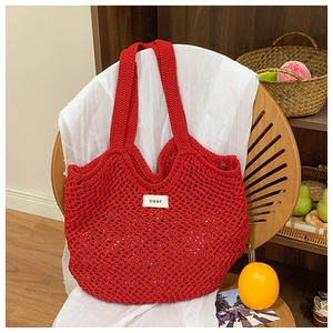 Détail du sac cabas en maille crochetée rouge avec étiquette blanche ouur tissée