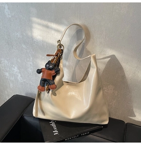 Detailed macro of cream faux leather hobo bag texture and cat-shaped pendant accessory