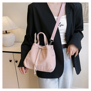Detail shot of pink nylon drawstring bucket bag worn cross-body on a fashion model