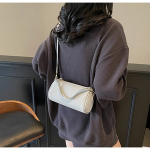 Detailed view of cream leather cylinder crossbody bag shown on model for daily styling
