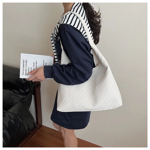 Detail of white woven tote bag featuring chevron texture and wide shoulder strap