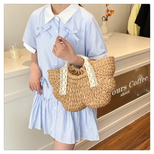 Detail of hand-woven straw bag with white lace handles and brown drawstring lining