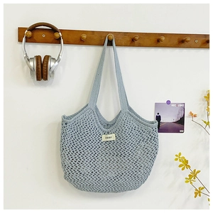 Gros plan détaillé du sac filet bleu clair tissé à la main avec texture de maille ajourée