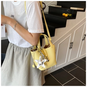 Detalle del bolso de cubo amarillo con textura de lichi, colgante de estrella y metal