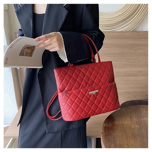 Detail view of red quilted diamond pattern faux leather backpack with silver metal logo plaque