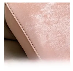 Gros plan d'un sac bandoulière rose montrant les coutures fines et le cuir matifié