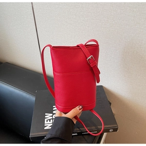 Close-up of red litchi texture bucket bag with adjustable strap on a dark background