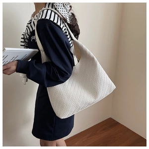 Close-up of white woven texture on a minimalist hobo bag with a spacious half-moon shape