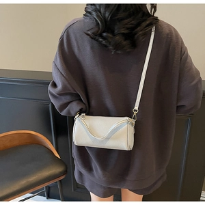 Detail of minimalist pebble leather crossbody bag with wave design and gold hardware