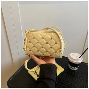 Close-up of cream quilted shell bag with sparkling rhinestone studs and metal zipper