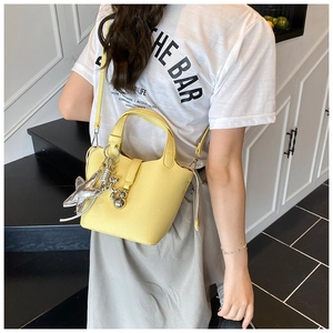 Detalle del bolso bombonera amarillo con grabado de lichi y colgantes de plata