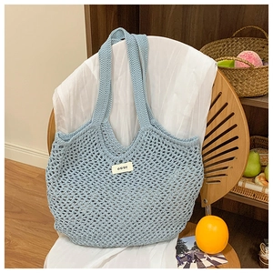 Gros plan d'un sac cabas en maille crochetée bleue avec étiquette tissée 'ouur' épurée