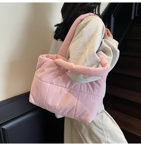 Sac cabas rose matelassé à coutures carrées porté par un mannequin dans un cadre moderne