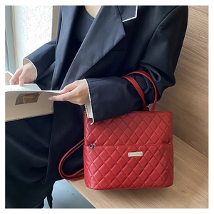 Macro shot of red quilted faux leather bag texture with metal zipper and logo plate