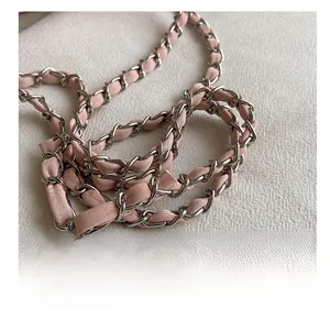 Détail de la bandoulière en cuir rose tressé et chaîne en métal argenté pour sac femme