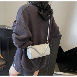 Detail view of light grey cylinder crossbody bag with fine lychee grain leather texture