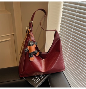 Close-up of deep red Hobo bag with cracked leather texture and a small cat charm accessory