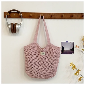 Détail du sac cabas rose au crochet ajouré avec étiquette blanche de style bohème