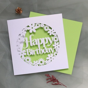 Detail of laser-cut Happy Birthday card with intricate floral patterns and green envelope
